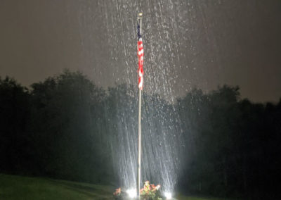 Rain coming down on a flag with lights beaming up installed by KL Tyndale Inc in Harrisburg, PA